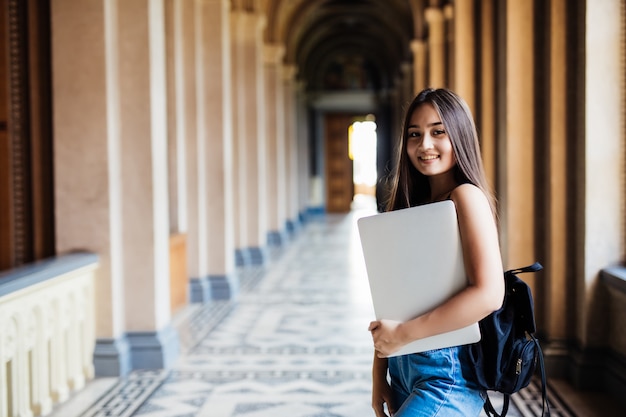 Giovane studente asiatico nel campus universitario con il computer portatile