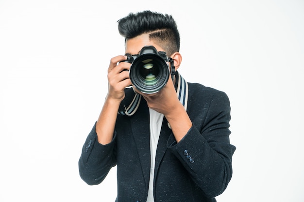 Giovane uomo asiatico con la macchina fotografica isolata su fondo bianco. Concetto di fotografo