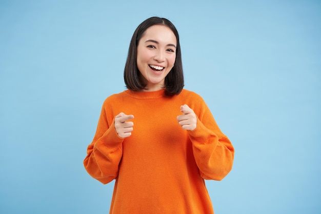 Foto gratuito hai ottenuto questo buon lavoro, una donna coreana entusiasta indica la telecamera con pistole a dito e sorride enco