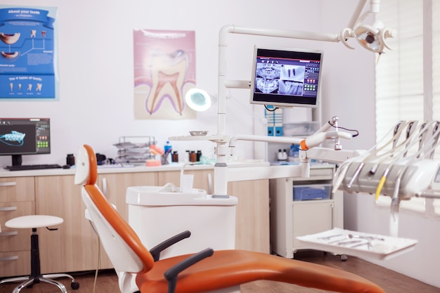 Interno del gabinetto moderno del dentista e della sedia medica. Armadio per stomatologia senza nessuno dentro e attrezzatura arancione per il trattamento orale.