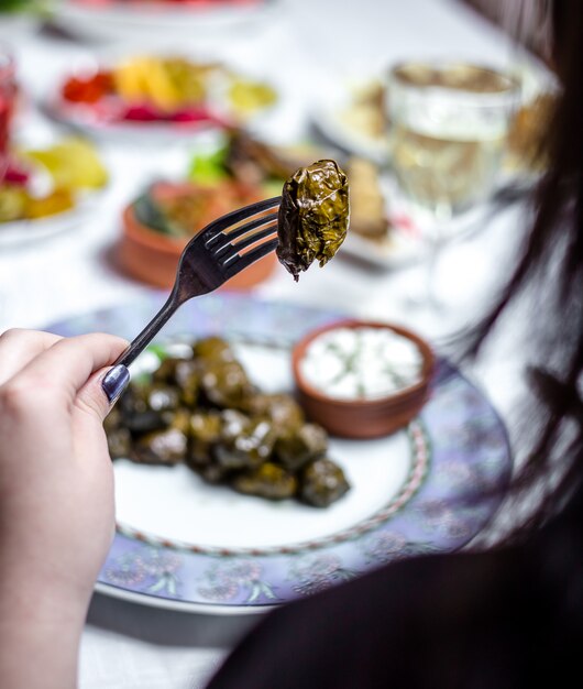 L'uomo tiene la forcella con foglie d'uva dolma pianura vista laterale