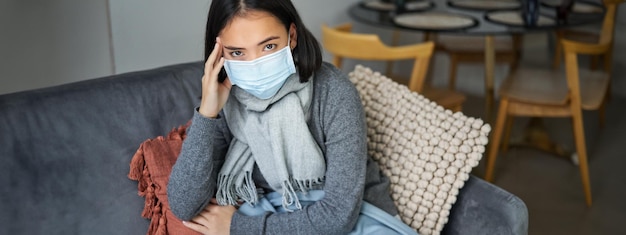 La donna con la maschera medica resta a casa con i dispositivi di protezione individuale mentre prende l'influenza