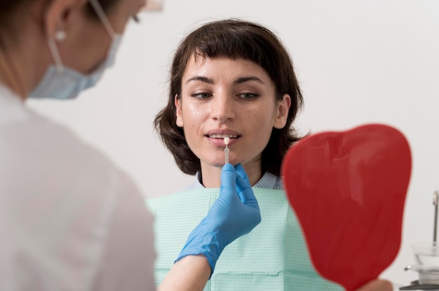 Paziente femminile che si guarda allo specchio nell'ufficio del dentista