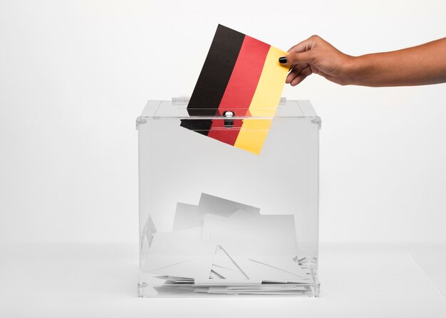 Persona che mette la carta della bandiera della Germania nell'urna