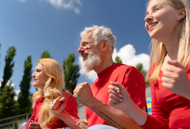 Persone che guardano insieme una partita di calcio in una giornata di sole