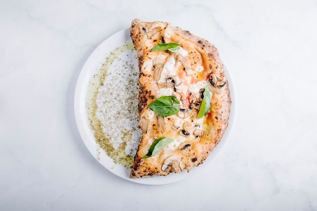 Pizza con funghi, mozarella e foglie di basilico.