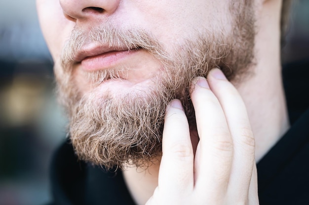 Foto gratuito primo piano un giovane si tocca la barba con la mano