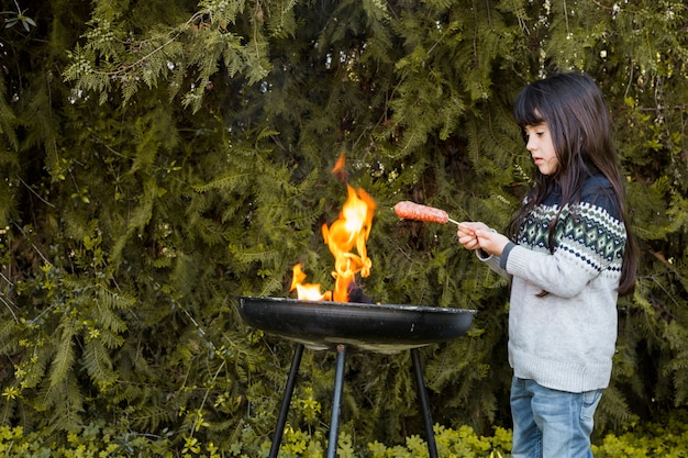 Foto gratuito ragazza grigliare salsicce sul barbecue all&#39;aperto