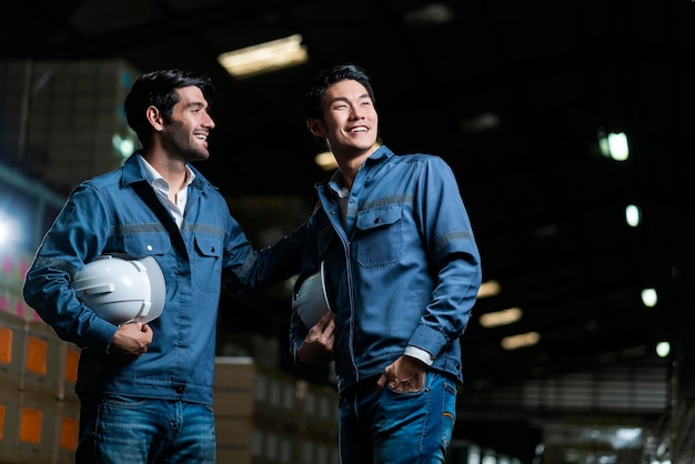 Foto gratuito rilassati casual maschio asiatico e caucasico ingegnere lavoratore personale in uniforme conversazione felice dopo il lavoro in background di distribuzione del magazzino