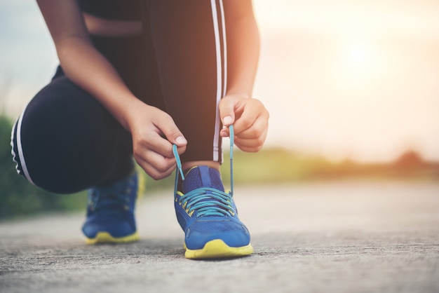 Scarpe da vicino Corridore femminile che lega le sue scarpe per un esercizio di jogging