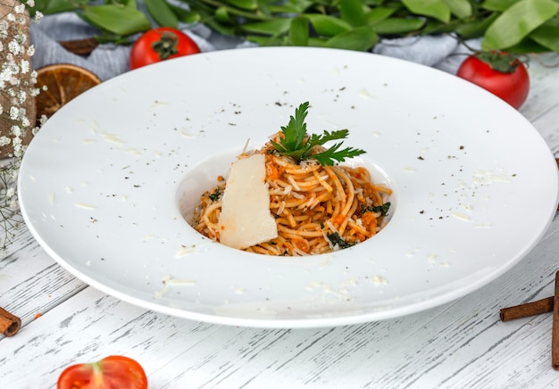 Foto gratuito spaghetti cremosi di carote con pomodoro, guarniti con prezzemolo e parmigiano