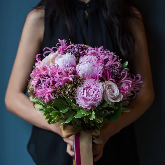 Foto gratuito una ragazza che tiene un mazzo di tipi di fiori viola con due mani