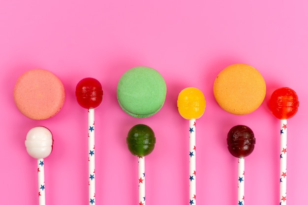 Foto gratuito una vista dall'alto macarons francesi colorati con lecca-lecca su rosa, zucchero dolce torta