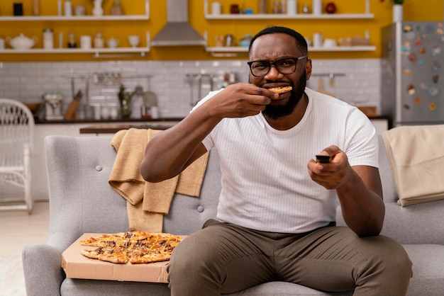 Uomo che guarda la tv e mangia pizza