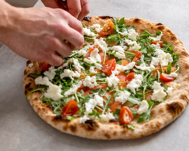 Foto gratuito uomo di alto angolo mettendo la mozzarella sulla pasta per pizza al forno con fette di salmone affumicato