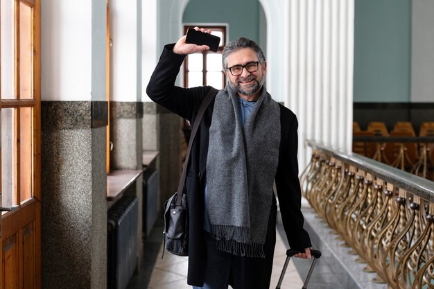 Uomo sorridente del colpo medio che viaggia con il bagaglio