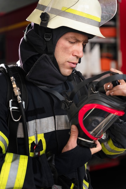 Vigile del fuoco maschio alla stazione in tuta e casco