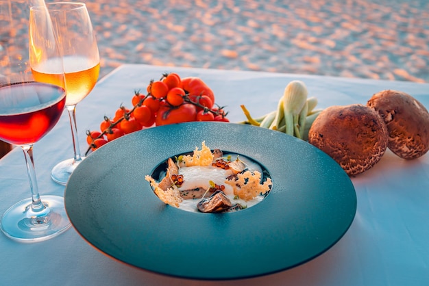 Antipasto al tramonto con vini e verdure fresche sul tavolo da pranzo in spiaggia. Sfondo di cibo di lusso