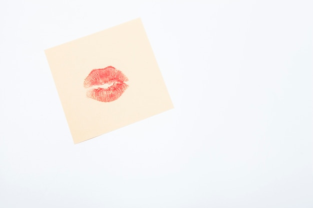 Foto bacio del rossetto rosso su un pezzo di carta per appunti giallo