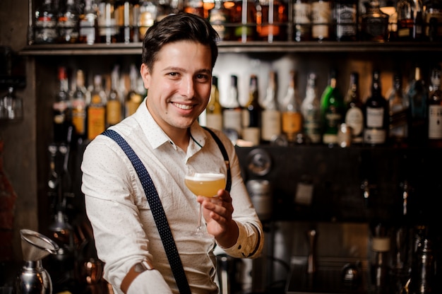 Foto barista sorridente in possesso di un cocktail al bancone del bar