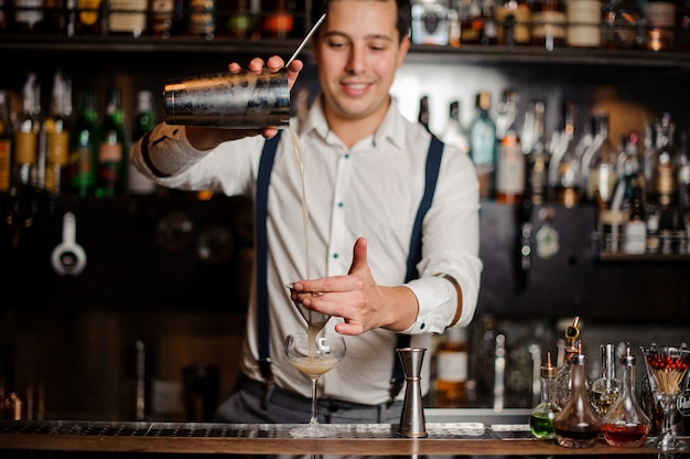 Foto barista sorridente sta facendo un cocktail al bancone del bar