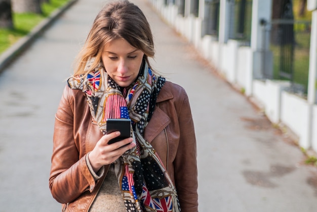 Bionda carino parlando su un telefono cellulare. Pretty giovane donna caucasica parlando al telefono all&#39;aperto nel parco