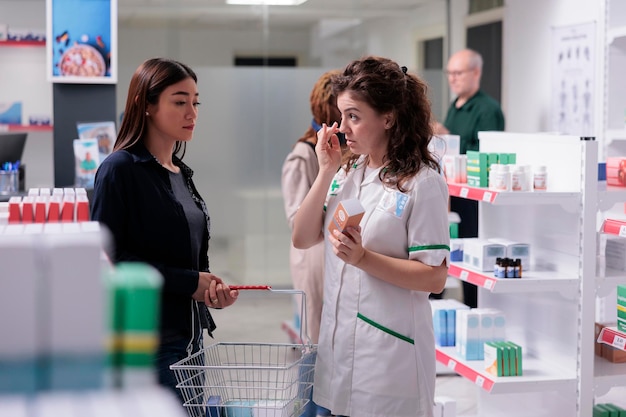 Cliente donna che parla con un utile specialista in farmacia sulla prescrizione di SPF in farmacia. Farmacista in uniforme medica che vende prodotti farmaceutici, spiegando l'importanza dell'assistenza sanitaria.