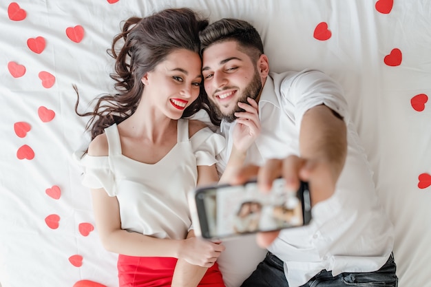 Coppia l'uomo e la donna che fanno il selfie sul telefono sul letto a casa