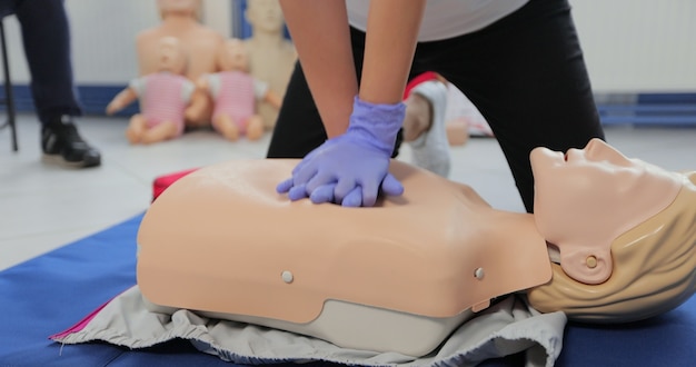 Donna che dimostra la RCP su manichino in classe di primo soccorso.