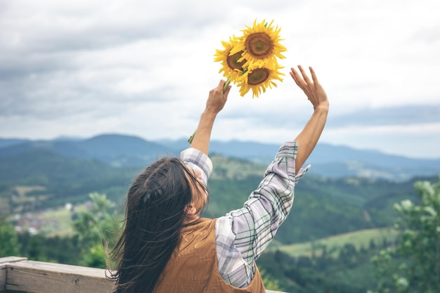 Donna con un mazzo di girasoli in natura in montagna