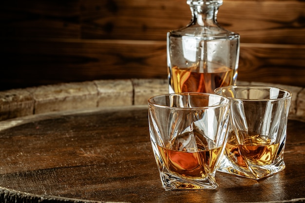 Due bicchieri di brandy o cognac e bottiglia sul tavolo di legno