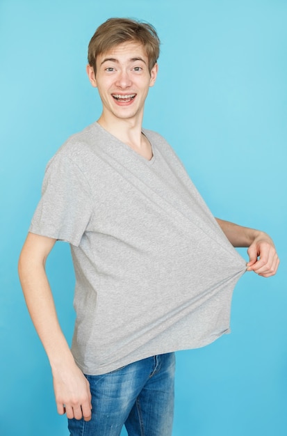 Foto giovane adolescente maschio in maglietta grigia su sfondo blu dopo la perdita di peso