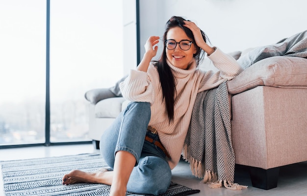 Giovane bella donna in abiti casual e con gli occhiali seduto a casa da solo.