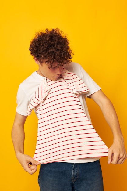 Foto giovane uomo dai capelli ricci maglietta a righe in posa di abbigliamento estivo sfondo giallo inalterato