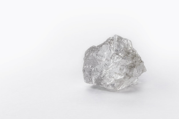 Grande pietra grezza del diamante sulla superficie bianca isolata.