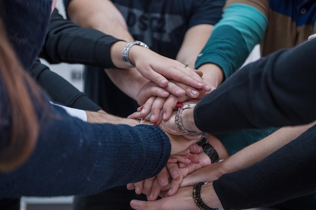 Gruppo di giovani studenti in aula di elettronica che celebrano con successo il progetto finito tenendo le mani insieme, concetto di istruzione e tecnologia