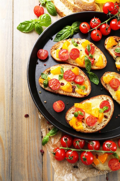 Gustose bruschette con pomodori in padella sul vecchio tavolo di legno