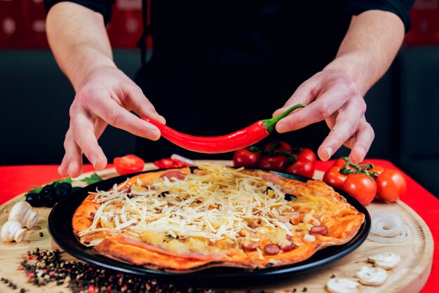 Il cuoco sta preparando la pizza. Aggiunge gli ingredienti