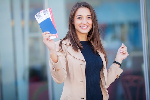 Immagine della donna europea che ha bei capelli marroni che sorridono mentre tiene i biglietti del passaporto e dell&#39;aria