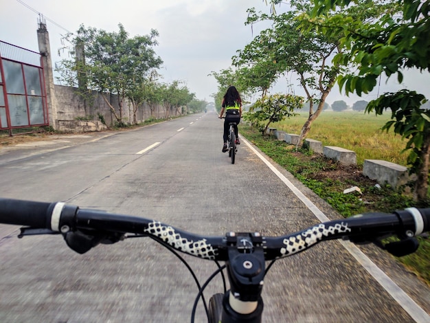 Immagine ritagliata della maniglia di una bicicletta contro una donna in bicicletta sulla strada