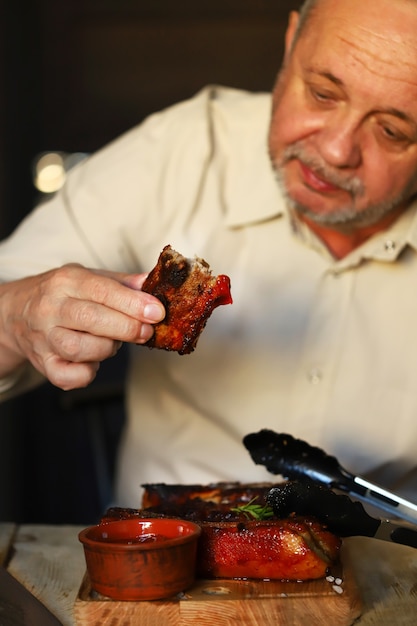 L'uomo mangia gustose costolette di maiale alla griglia