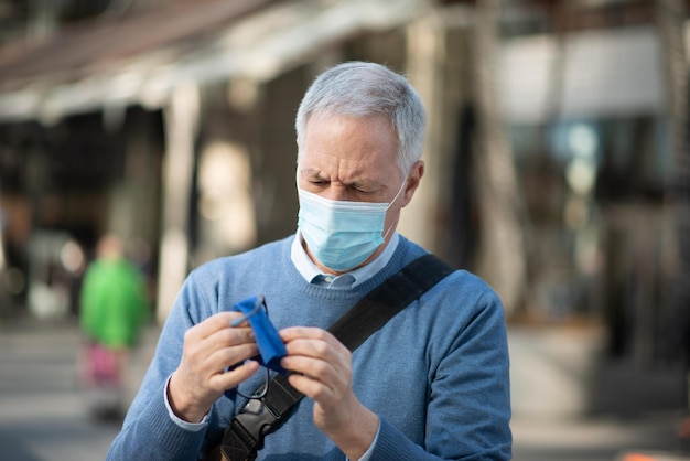 L'uomo pulisce gli occhiali appannati a causa del concetto di visione del coronavirus covid della maschera