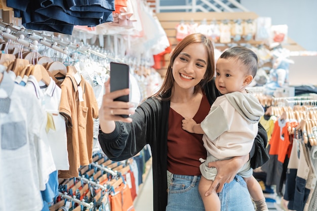 La madre asiatica si fa un selfie con suo figlio mentre fa shopping nel centro commerciale