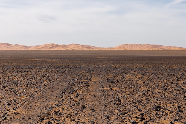 La strada attraverso il deserto di pietra per le dune di sabbia di erg chebbi deserto del sahara in Marocco