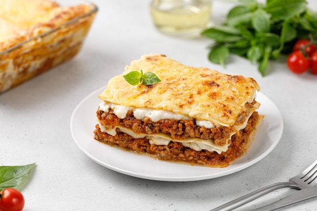 Lasagne italiane fatte in casa Deliziose lasagne con ragù alla bolognese e formaggio su piatto bianco