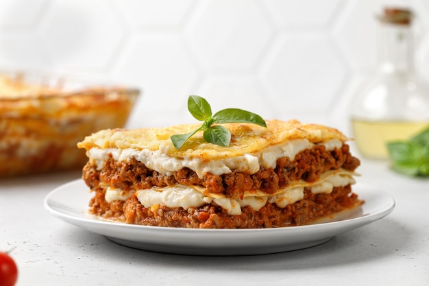 Lasagne Lasagne italiane fatte in casa con ragù di carne bolognese e basilico su piatto bianco