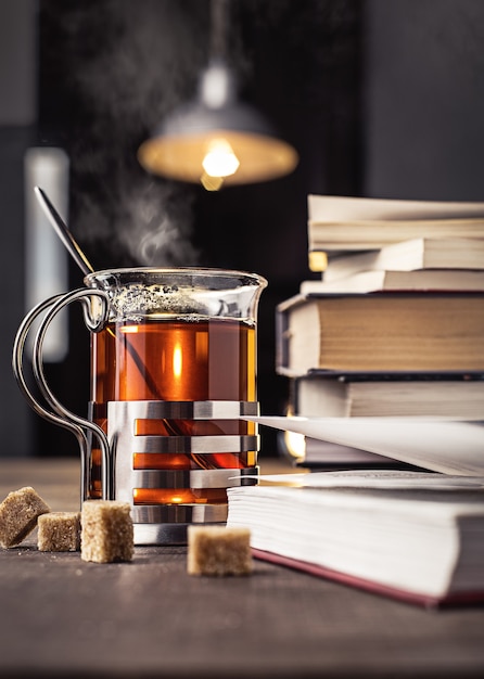 Libri e un bicchiere di tè con pezzi di zucchero sul tavolo