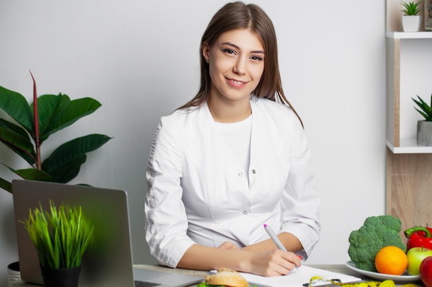 Nutrizionista femminile con frutti che lavorano alla sua scrivania