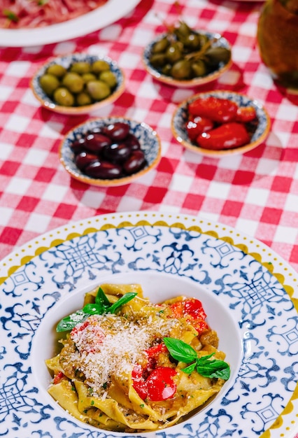 Foto pasta italiana con pomodori, parmigiano, basilico e olive