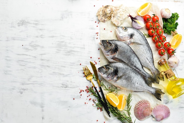 Pesce crudo di dorado con spezie. Su uno sfondo di legno bianco. Vista dall'alto.